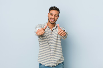 Young handsome filipino man with thumbs ups, cheers about something, support and respect concept.