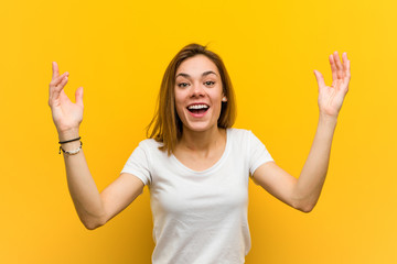 Young natural caucasian woman receiving a pleasant surprise, excited and raising hands.