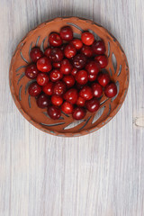 Red sweet cherries in a clay dish on a white wooden table