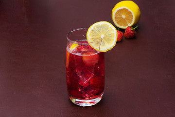 Drink with ice from strawberries on a dark background. Fresh strawberry cocktail. Fresh summer cocktail with strawberry and ice cubes. Glass of strawberry soda drink on dark background.