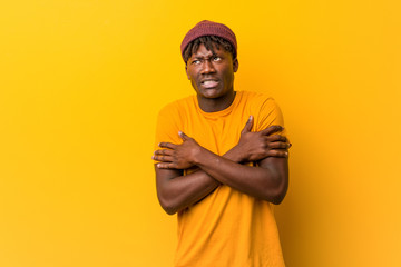 Young black man wearing rastas over yellow background going cold due to low temperature or a...
