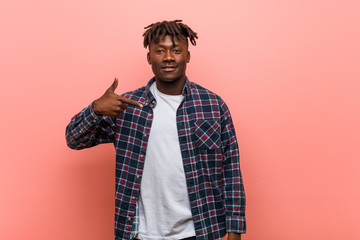 Young african black man person pointing by hand to a shirt copy space, proud and confident
