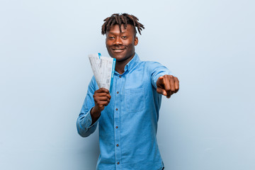 Young rasta black man holding an air tickets cheerful smiles pointing to front.