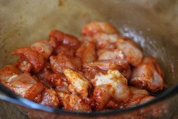 marinated chicken indian tandoori seasoning in a bowl, on wooden background, in the kitchen