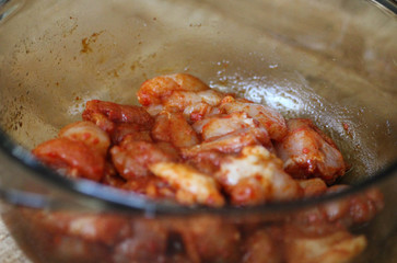 marinated chicken indian tandoori seasoning in a bowl, on wooden background, in the kitchen
