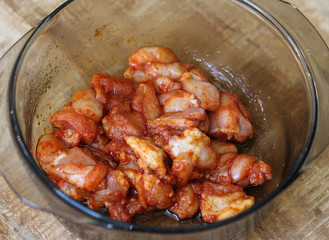 marinated chicken indian tandoori seasoning in a bowl, on wooden background, in the kitchen