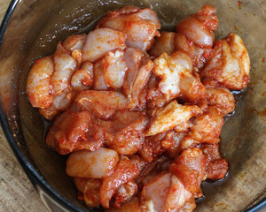marinated chicken indian tandoori seasoning in a bowl, on wooden background, in the kitchen