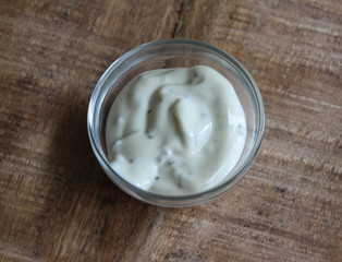 garlic sauce in a glass bowl, on a wooden background