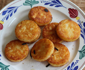 fresh baked hommade potato pancakes, also named rosti, hash browns, kartoffelpuffer, latkes, draniki - on white plate on wooden background.