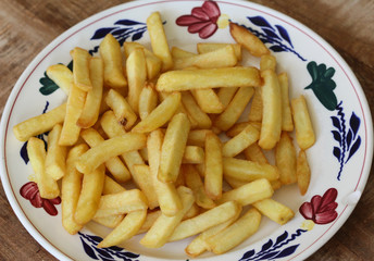 Tasty homemade french fries on white plate, on wooden table background
