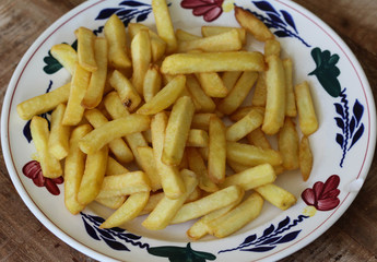 Tasty homemade french fries on white plate, on wooden table background