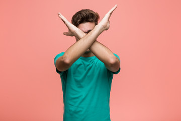 Young cool caucasian man keeping two arms crossed, denial concept.