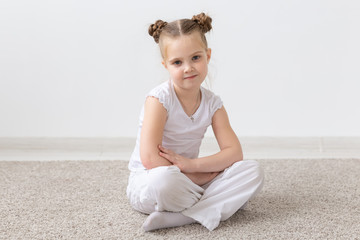 Children and kids concept - Little child girl dressed in white shirt sitting on the floor with thoughtful face