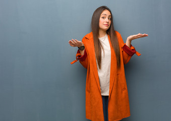Young natural woman doubting and shrugging shoulders