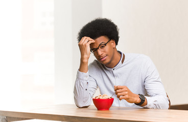 Young black man having a breakfast worried and overwhelmed