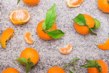 Fresh clementines with green leaves on a stone background