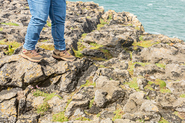 Woman hiker boots on rocks walking over limestone rocks in Burren, Geopark and Geosite, Wild Atlantic Way, wonderful spring day in County Clare in Ireland