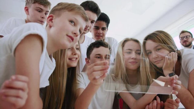 Group portrait of amazed attractive young students teens using a virtual technology tablet during a class. Future tech innovation and education concept.