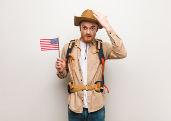 Young redhead explorer man worried and overwhelmed. Holding an united states flag.
