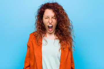 Young redhead elegant woman screaming very angry and aggressive.