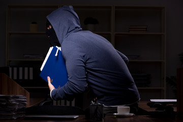 Male thief in balaclava in the office night time 