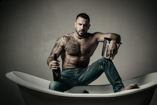 single man drink champagne from bottle. cold alcohol with ice bucket. brutal sportsman torso. sport and fitness, health. sexy abs of tattoo man. male loneliness. muscular macho man with athletic body