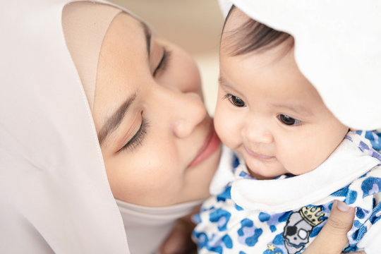 Asian Muslim mother woman kissing and hugging a  baby in her arms. family concept.