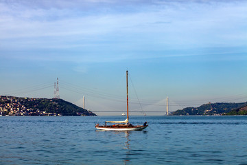 a small white sailing boat is anchored on Marmara Sea. You can see 3rd Bosphorus (Yavuz Sultan Selim) Bridge from Sariyer coast, Istanbul, Turkey