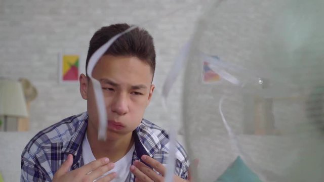 Young asian man saved from the heat sitting in front of a working fan the concept of heat close up slow mo