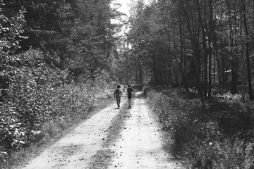 Children's figures in the distance on a forest dirt road