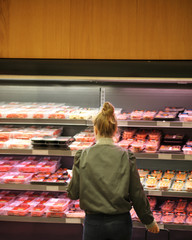Woman purchasing a packet of meat at the supermarket 