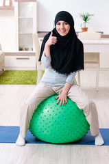 Young woman in hijab doing exercises at home 