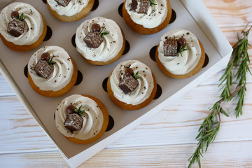 Packing Cupcakes with vanilla cream, decorated with waffles and rosemary