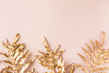 Flat lay of gold tropical palm leaves Monstera on pink background. Top view of minimal concept.