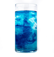 Blue food coloring diffuse in water inside glass with empty copyspace area for slogan or advertising text message, over isolated white background.