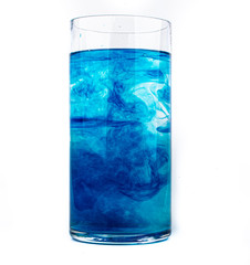 Blue food coloring diffuse in water inside glass with empty copyspace area for slogan or advertising text message, over isolated white background.