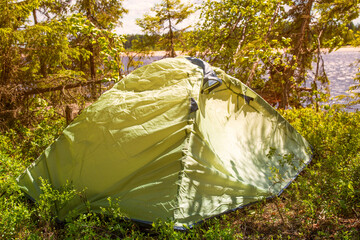 Tourist tent in the woods near the river. Tourist in nature.