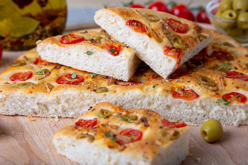 Focaccia with tomatoes and olives. Traditional Italian bread. Homemade baking. Close-up, selective focus.