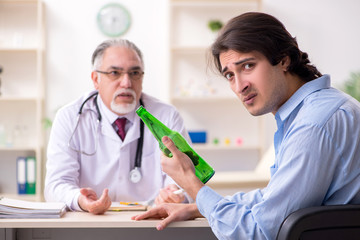 Obraz premium Young male alcoholic visiting old doctor 