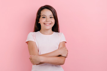 Obraz premium Little girl standing with folded her hands over pink background