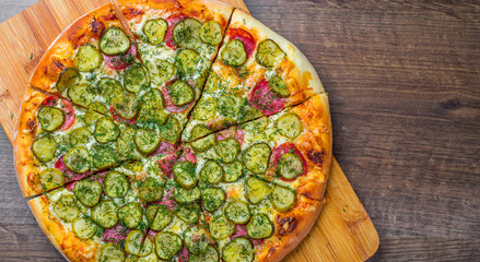 Pizza with Mozzarella cheese, salami, bacon, Tomato sauce, fresh dill, Spices and pickled cucumbers. big dill pizza on wooden table background