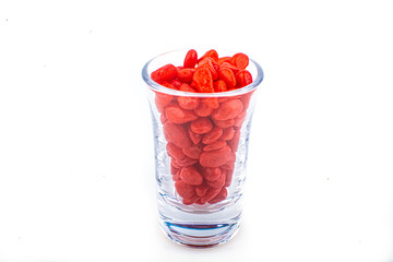 Red pebbles stone inside glass with empty copyspace area for slogan or advertising text message, over isolated white background.