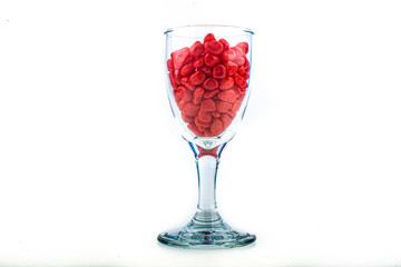 Red pebbles stone inside glass with empty copyspace area for slogan or advertising text message, over isolated white background.