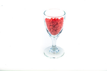Red pebbles stone inside glass with empty copyspace area for slogan or advertising text message, over isolated white background.