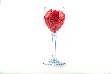 Red pebbles stone inside glass with empty copyspace area for slogan or advertising text message, over isolated white background.