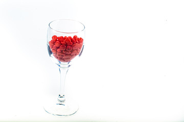Red pebbles stone inside glass with empty copyspace area for slogan or advertising text message, over isolated white background.