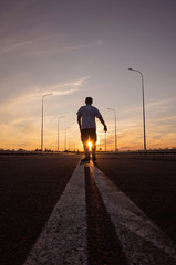 A Caucasian man with a short haircut in a white T-shirt and shorts riding on rollers on an empty...