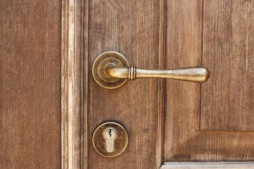 Fototapeta premium Brown wooden entrance door with bronze door handle and modern keyhole