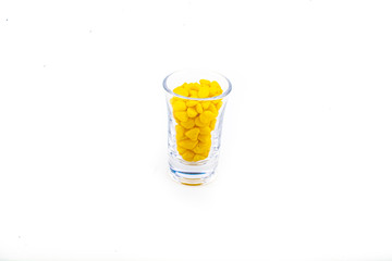 Yellow pebbles stone inside glass with empty copyspace area for slogan or advertising text message, over isolated white background.