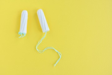 Two cotton tampons for women monthly menstruation with selective focus on yellow background. Soft white tampon for female period days on neutral backdrop with empty space for text. Healthcare 